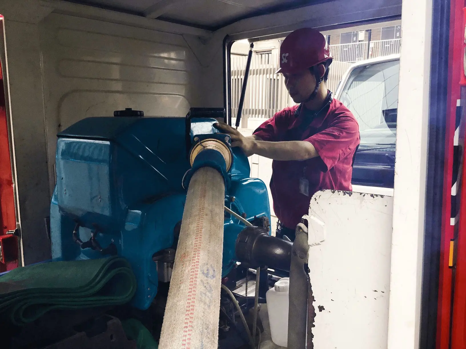 作業着を着た男性が連結送水管耐圧試験専用車車内のポンプを使用している写真