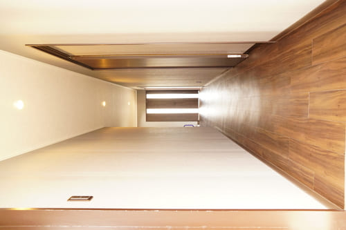 内装工事後の写真 木目のあるフローリングに、スライドドアを取り入れた細長い廊下