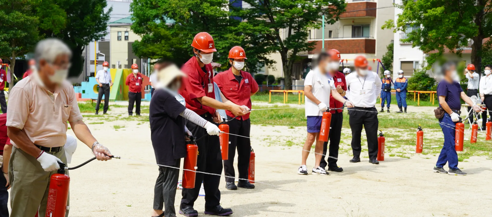 新日本コーポレーションの安全大会の様子で、地域の方々と一緒に消火器を使って消火体験を行っている写真